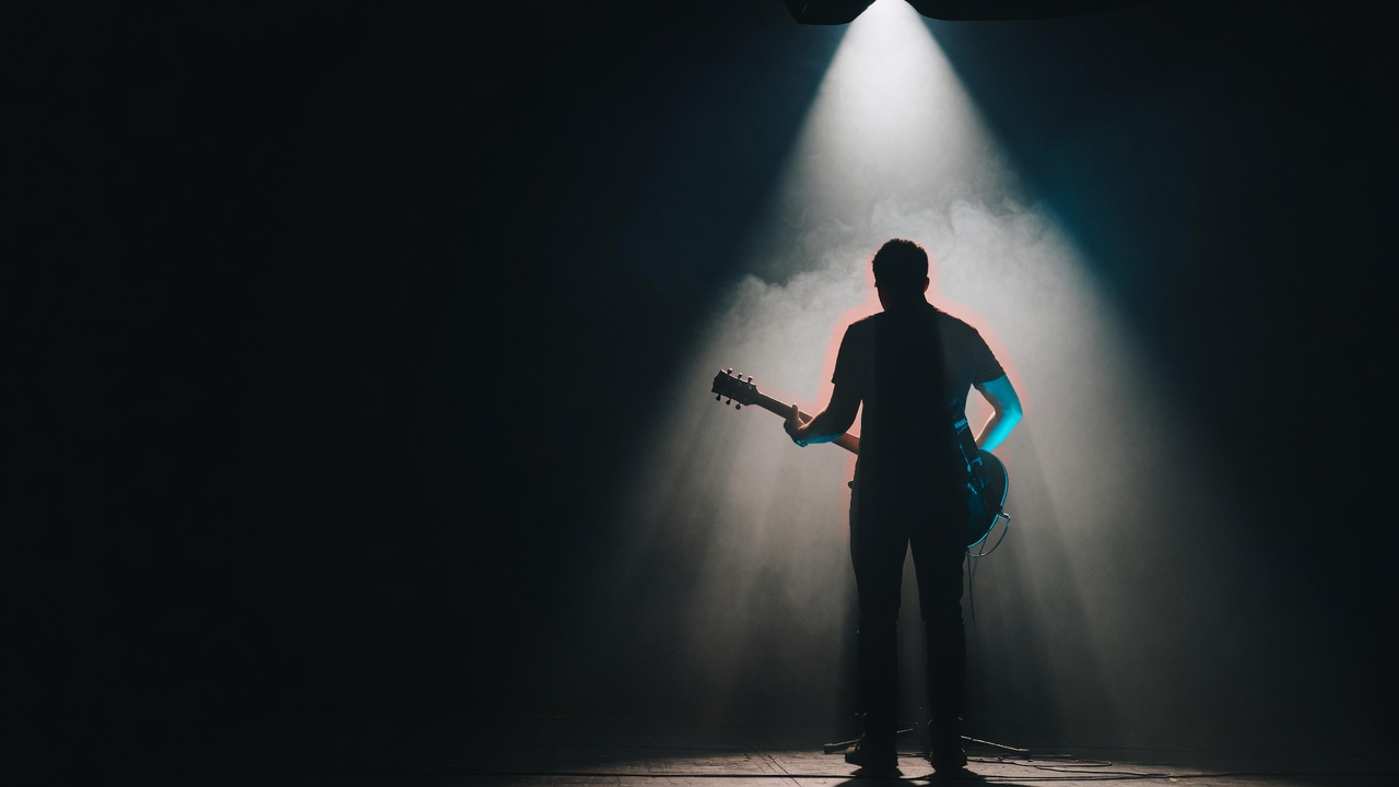 A performer stepping into a single spotlight on a dark stage